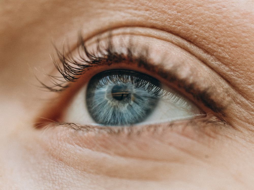 Close no olho azul com foco na íris, ilustrando exames relacionados à retina do olho descolada e saúde ocular avançada.