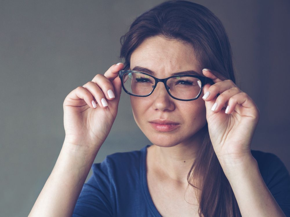 Mulher com dificuldade de enxergar claramente, um dos sinais que podem indicar o que é visão distorcida e necessidade de avaliação oftalmológica.